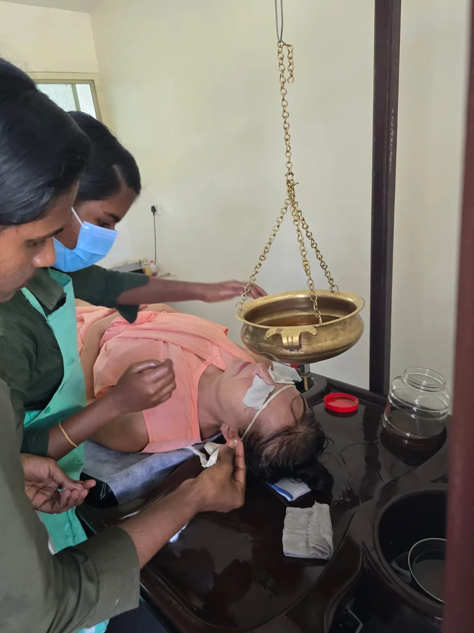 Shirodhara protseduur Kerala ajurveedakeskuses: terapeut valab sooja õli laubale